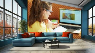 young woman with textbook using online school on laptop Wall mural