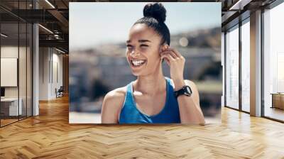 Fitness, happy and woman with earphones for music entertainment with wireless tech on workout rest. Exercise, training and wellness girl in city with smile streaming bluetooth audio on break. Wall mural