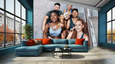 Fitness, sports and group of friends sitting on stairs with a smile, positive mindset and happiness after fitness training or soccer match. Diversity with men and women athletes in London health club Wall mural