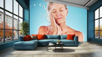 Senior woman, water and skincare for hydrate, hygiene and fresh clean treatment against a blue studio background. Happy elderly female touching face for smooth facial hydration or skin moisture Wall mural