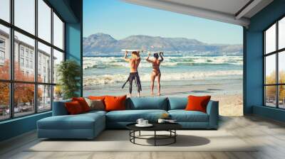 The perfect wave is heading our way. Shot of a young couple out at the beach with their surfboards. Wall mural