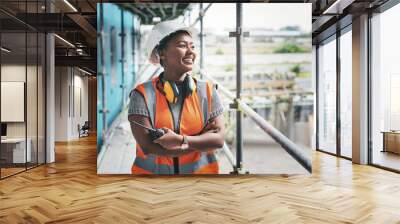 A happy, smiling and cheerful young black woman or senior construction industry worker standing at a building site. A professional female employee working at housing or property development location Wall mural