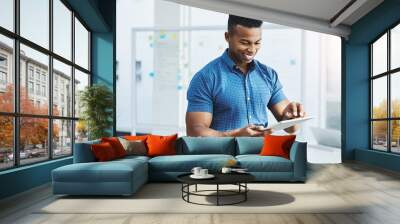 He always finds the greatest sources of inspiration online. Shot of a young businessman using a digital tablet in an office. Wall mural