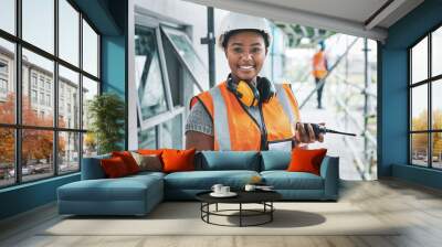 Portrait of proud black construction worker leading with power while managing site logistics on tablet. Happy female engineer supervising a building project and inspection of architectural details Wall mural