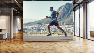 Running is one of the best ways to stay fit. Shot of a young handsome man running outdoors. Wall mural