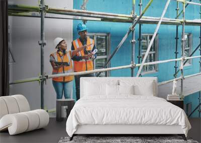 Shaping the future of construction with the help of smart apps. Shot of a young man and woman using a digital tablet while working at a construction site. Wall mural