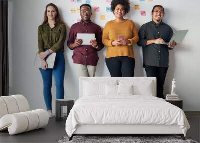 Were keeping the connection going strong. Full length shot of a group of a young businesspeople standing together and using their digital devices at work. Wall mural