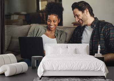 Were updating all our blogs today. Shot of a happy young couple using a laptop while relaxing on a couch in their living room at home. Wall mural