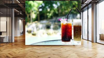 A tropical dink in summer, ice lemon tea and ice coffee, 2 glasses on the table near the pool and tree, fresh and relax concept, drink menu design with a copy space, good thing for summer in Thailand Wall mural