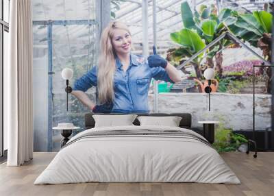 Beautiful woman works with flowers at greenhouse. Wall mural