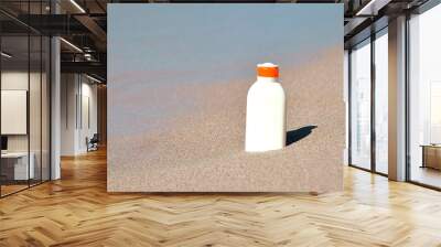 Bottle with sun protection cream on sand texture. Wall mural