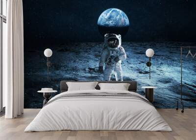 Astronaut walks on the surface of the moon overlooking the blue planet Earth. Lunar mission and exploration. Space man on the moon Wall mural