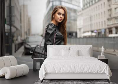 Beautiful stylish business lady in fashionable black clothes with a dress and a fashion black leather bag is walking in the city. Urban elegant girl Wall mural