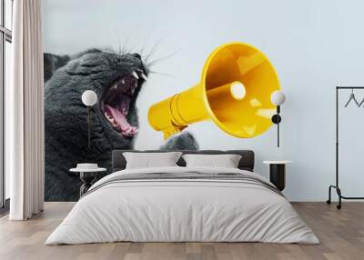 Funny grey cat screams with a yellow loudspeaker on a blue background, creative idea. Fun pet kitten speaks into a megaphone. Management and advertising, concept Wall mural