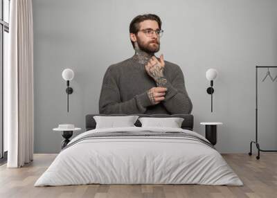 Stylish handsome successful hipster man with a beard and hairstyle with fashionable glasses in a knitted vintage sweater on a white background in the studio Wall mural