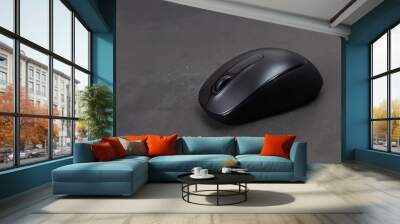 Black wireless mouse on gray background, dark tone. Wall mural