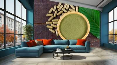 Mitragyna Speciosa Korth or kratom powder on wooden bowl wtih capsules and green leaf on rustic wooden background.   Wall mural