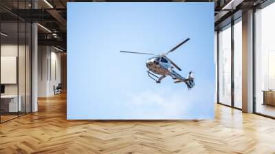 Flying helicopter in blue sunny sky Wall mural