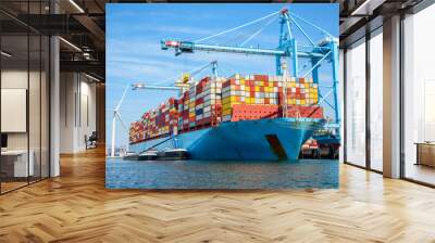 Large cargo ship full loaded with containers moored to a container terminal on a sunny summer day Wall mural