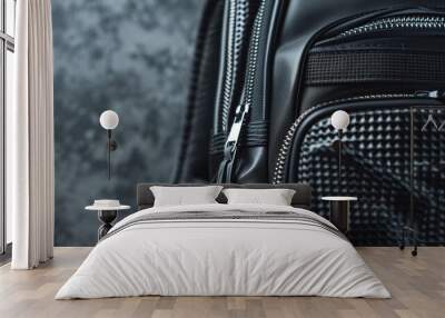 High-detail close-up of a black backpack with zippers and pockets, ready for the back to school season, on a textured gray background Wall mural