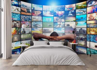 Man has fun watching a film and relaxing on a armchair. Concept of entertainment and streaming tv. Wall mural