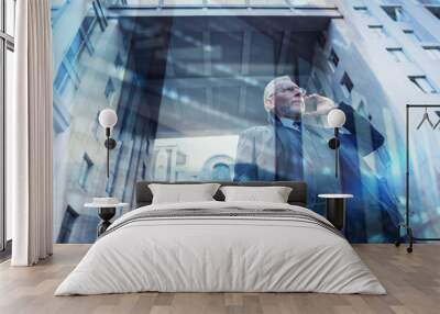 Senior businessman speaks on the mobile while walking in a modern city. Double exposure effect Wall mural