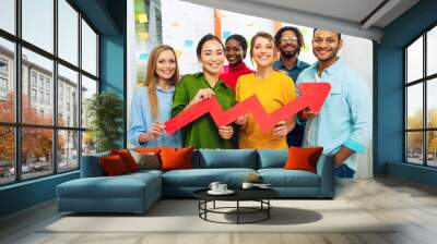 Young happy and colorful business team hold a red statistical arrow. Concept of growing, succesful and profit Wall mural