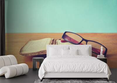 Old books with glasses on a wooden table. Wall mural