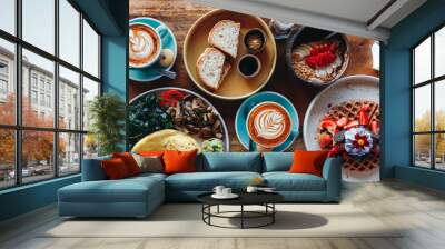 Morning breakfast on a table above, waffles with cream, berries, coffee, cappuccino, bowl, omlet with vegetables, bread with butter, avocado cream, vegan food, healthy food, meal. Wall mural