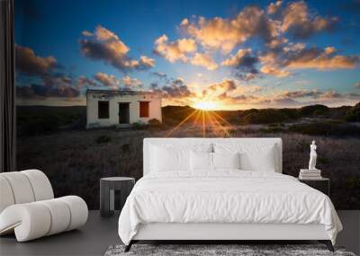 Old small deserted house in field with cloud sunset landscape Wall mural