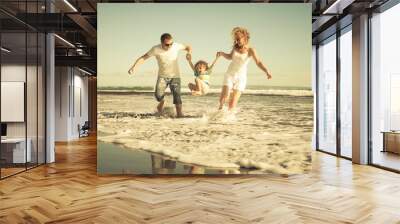 Happy family playing on the beach at the day time Wall mural