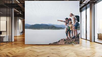 Happy family standing near the lake at the day time. Wall mural