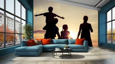 Happy family standing on the field at the sunset time. Wall mural