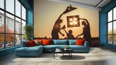 Happy family standing on the field at the sunset time. Wall mural