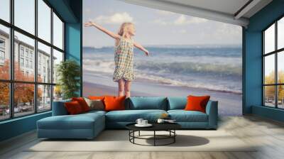 Happy Little girl  standing on the beach Wall mural