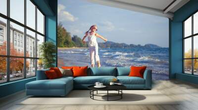 Little girl  dancing on the beach at the day time. Wall mural