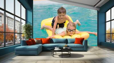 Two happy children playing on the swimming pool at the day time. Wall mural