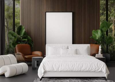 Modern living room with an empty vertical poster frame mockup on a wooden slat wall. The scene features two brown leather armchairs, a round coffee table, and large potted plants. Wall mural