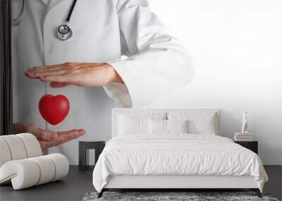 doctor in a white coat protecting with his hands a red heart with a lot of copy space on the right Wall mural