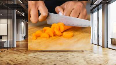 Detailed shot of a male cutting carrot on a wooden cutting board. Wall mural