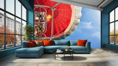 shot from below of a red hot air balloon with the burner lit and blue sky in the background Wall mural