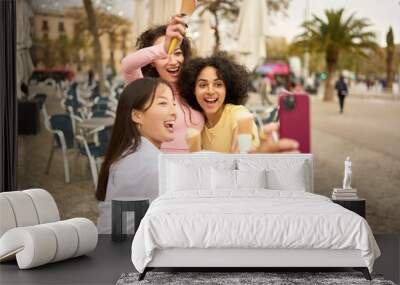 Young women enjoying ice cream and taking selfie outdoors Wall mural