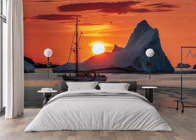 A large iceberg is floating in the ocean with a sailboat in the background Wall mural