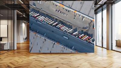 Aerial view of goods warehouse. Logistics center in industrial city zone from above. Aerial view of trucks loading at logistic center. View from drone. Wall mural