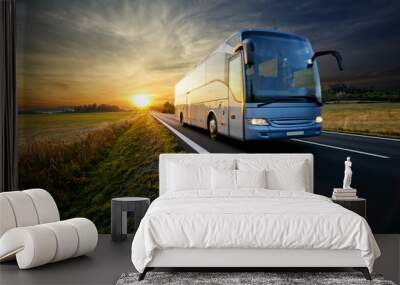 bus traveling on the asphalt road in rural landscape at sunset Wall mural