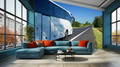 The white bus traveling on asphalt road lined avenue of trees in a rural landscape on a bright sunny day Wall mural