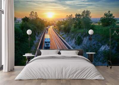 Three trucks driving on the highway in a rural landscape at sunset. View from above. Wall mural