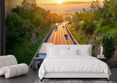 Three white truck and three private car driving on the asphalt road in a rural landscape at sunset with dramatic clouds. View from above. Wall mural