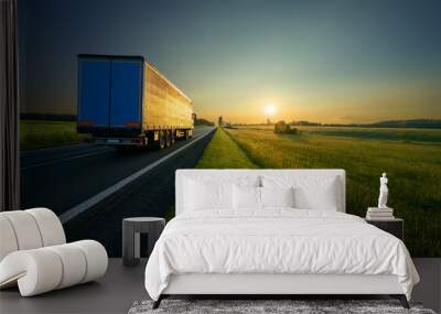 Truck driving on the asphalt road in a rural landscape in golden sunset colors Wall mural