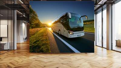 white bus traveling on the asphalt road around line of trees in rural landscape at sunset Wall mural